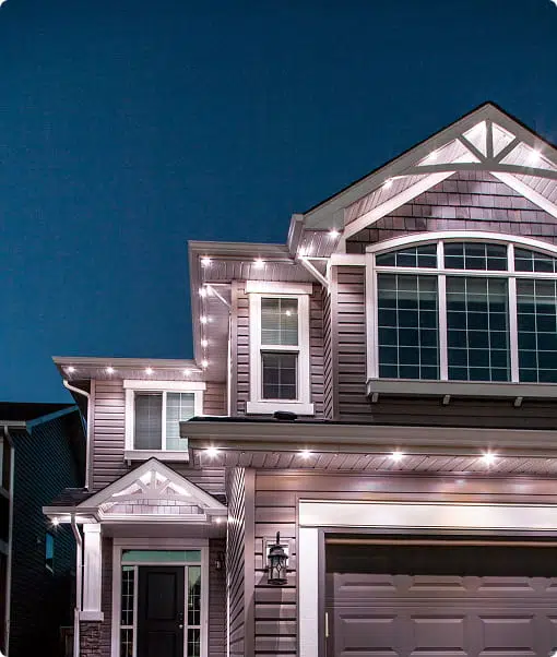 Bright holiday lights adorn a cozy, modern home against a twilight sky