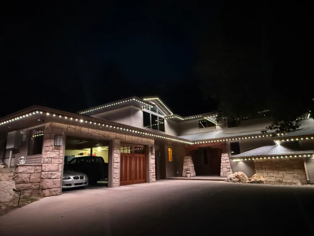 A beautifully illuminated modern house with decorative lights outlining its structure at night