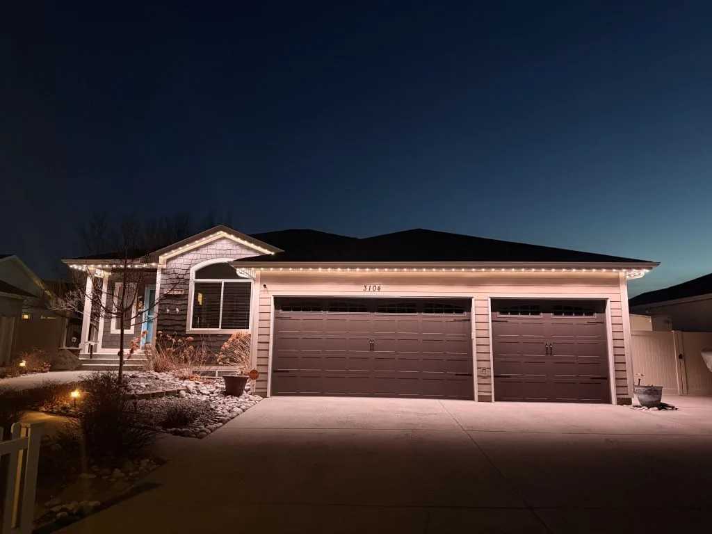 A house is illuminated by warm lights against a twilight sky